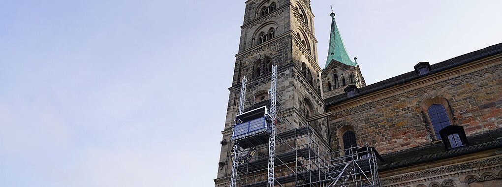 Ein Bauaufzug an einem historischen Kirchturm ermöglicht Handwerkern den sicheren Zugang zu den oberen Bereichen des Gebäudes.
