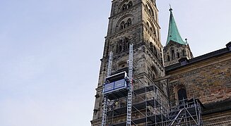 Ein Bauaufzug an einem historischen Kirchturm ermöglicht Handwerkern den sicheren Zugang zu den oberen Bereichen des Gebäudes.