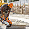 Ein orangefarbener Trennschleifer beim Einsatz auf einer Baustelle.