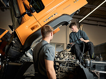 Zwei Servicetechniker bei der Wartung an einem Unimog.