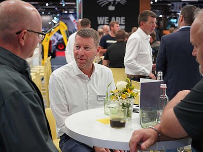 Drei Menschen im Gespräch auf einem Messestand.
