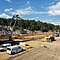 Ein gelber Raupenkran LR bei der Montage auf einer Baustelle unter blauem Himmel.