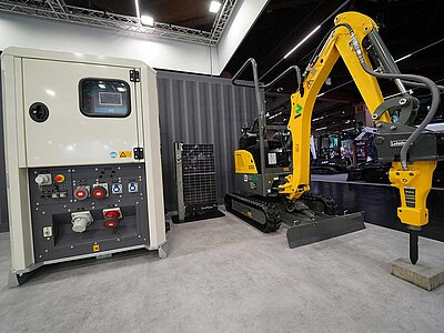 Zwei Ausstellungsexponate auf einem Messestand: ein Stromerzeuger und ein Minibagger.