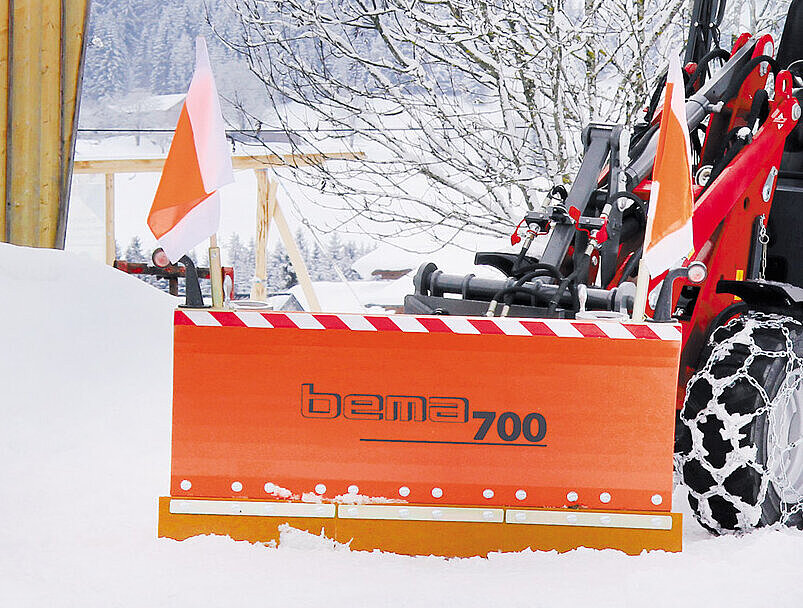 Baumaschine mit einem Schneeschild räumt Schnee