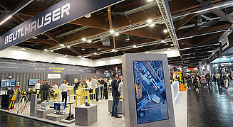 Ein Messestand in einer Messehalle mit Besucher und Messepersonal.
