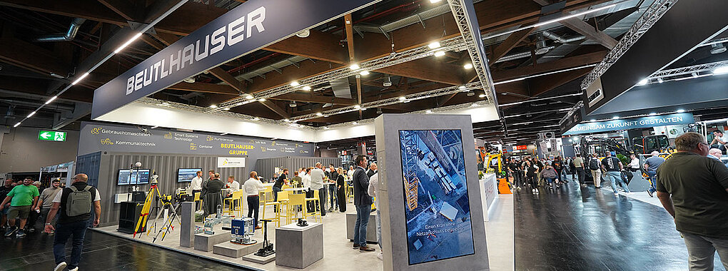 Ein Messestand in einer Messehalle mit Besucher und Messepersonal.