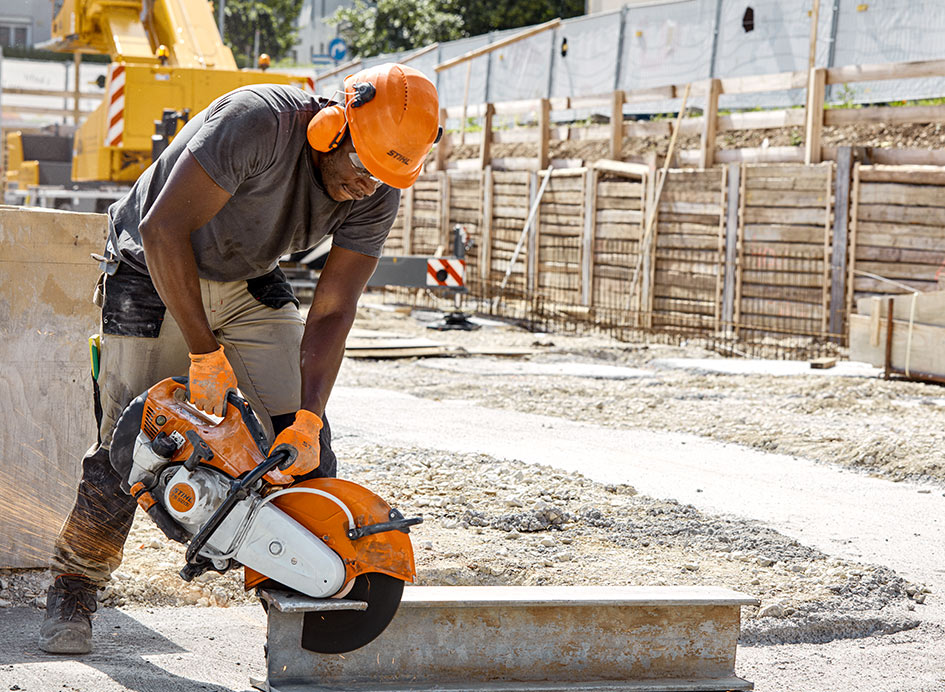 Ein orangefarbener Trennschleifer beim Einsatz auf einer Baustelle.