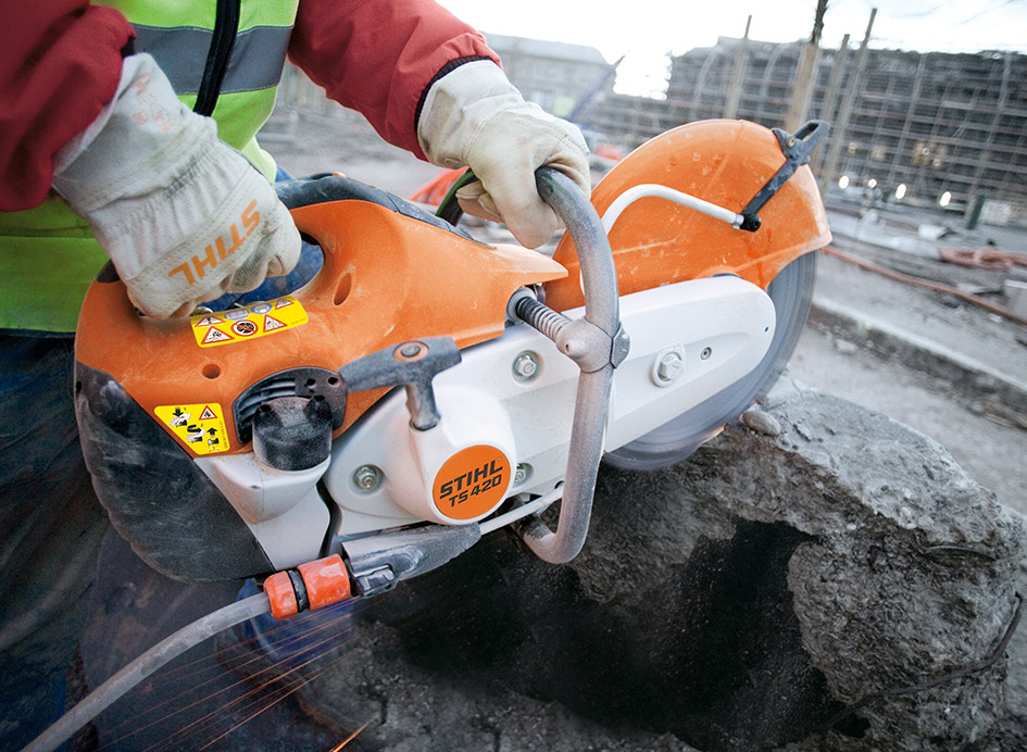 Ein orangefarbener Trennschleifer beim Einsatz auf einer Baustelle.