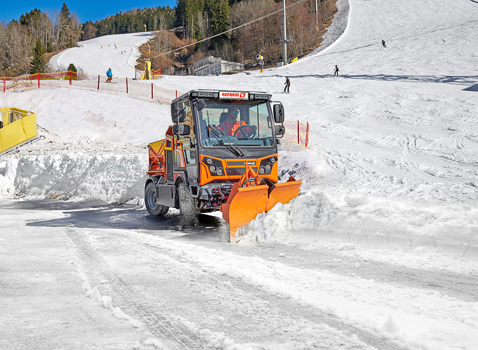 Ein orangefarbenes Fahrzeug mit Schneepflug