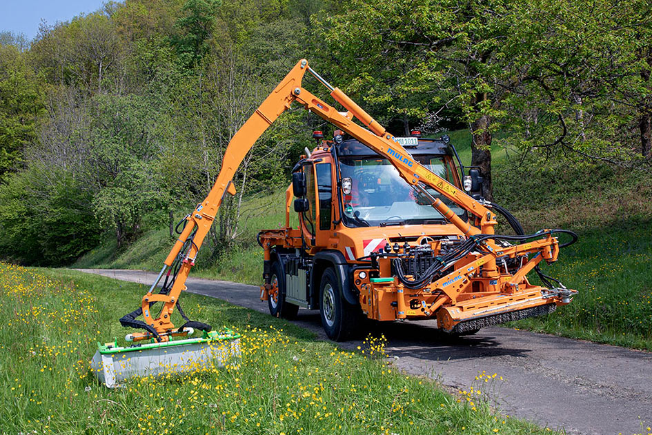 Mann im Unimog U 535 mäht an einer Straße